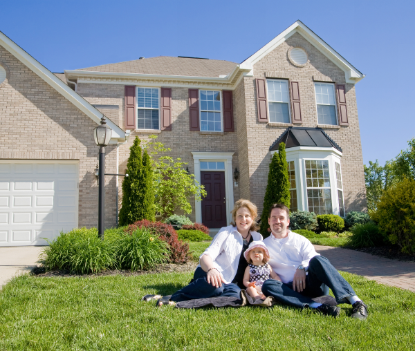 Happy family posing outside their house